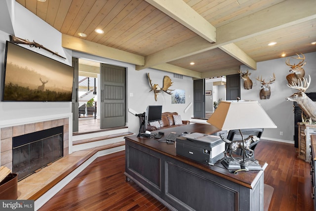 office area with beam ceiling, recessed lighting, a tile fireplace, dark wood-type flooring, and wooden ceiling