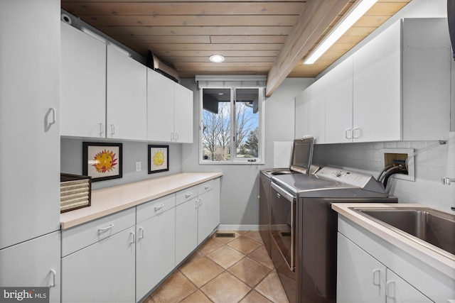 laundry area featuring washer and dryer, a sink, cabinet space, wooden ceiling, and light tile patterned floors