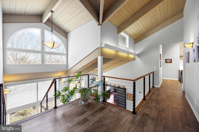 hallway with baseboards, beam ceiling, an upstairs landing, wood finished floors, and high vaulted ceiling