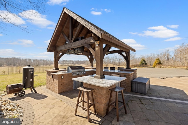 view of patio / terrace featuring fence, outdoor wet bar, area for grilling, a gazebo, and grilling area