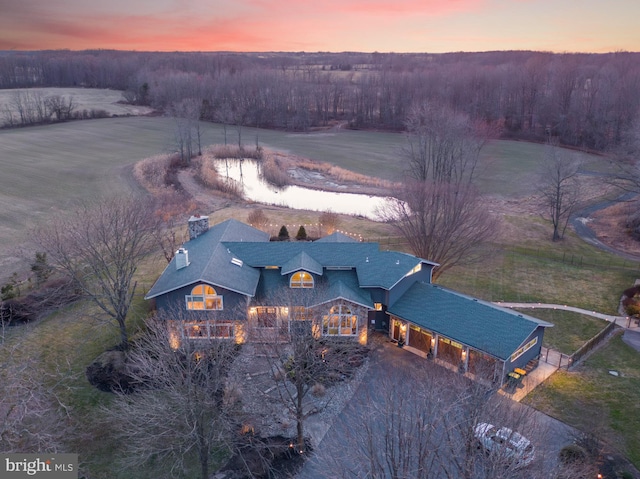 aerial view at dusk featuring a wooded view