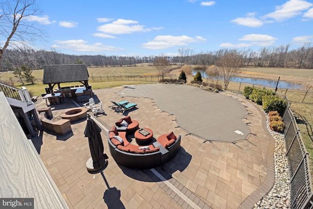 view of patio featuring a water view, fence, and an outdoor fire pit