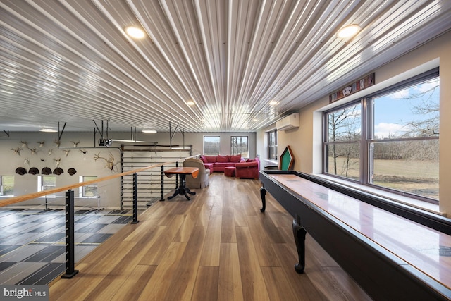 recreation room featuring wood finished floors and a wall mounted air conditioner