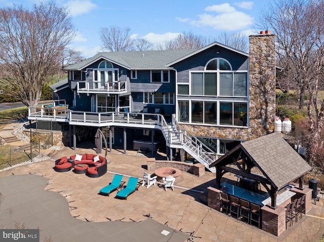 rear view of house featuring outdoor dry bar, a shingled roof, stairway, a balcony, and a patio area