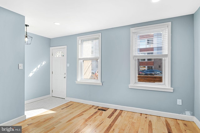 entryway with hardwood / wood-style floors, visible vents, and baseboards