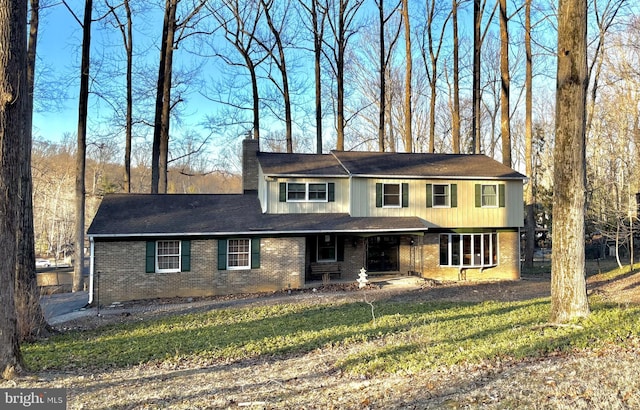 view of front of home with a front lawn, brick siding, and a chimney