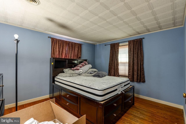 bedroom with visible vents, wood finished floors, and baseboards