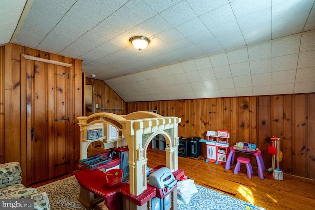 bedroom with lofted ceiling, wood finished floors, and wood walls