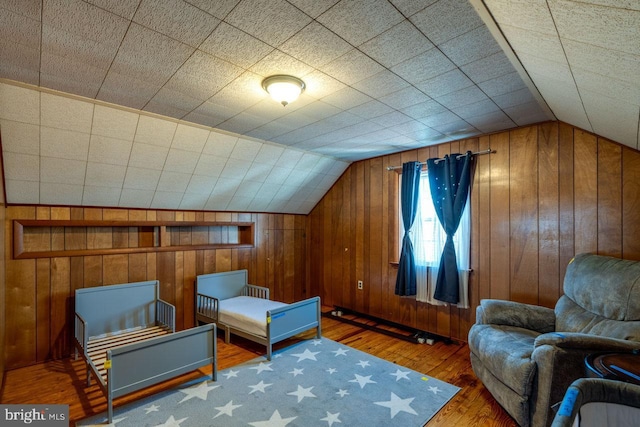 interior space featuring lofted ceiling, hardwood / wood-style floors, and wood walls