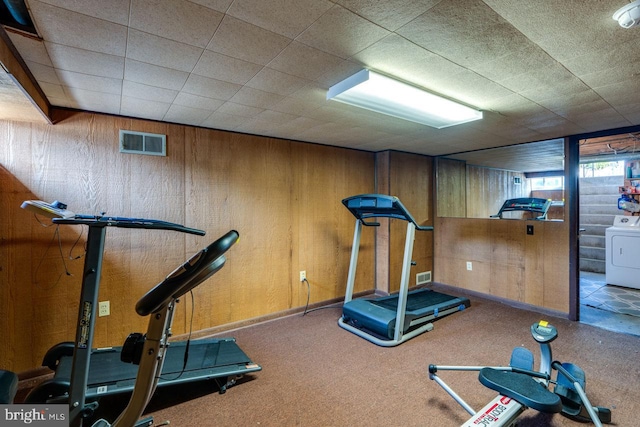 workout area featuring visible vents, washer / dryer, and wooden walls