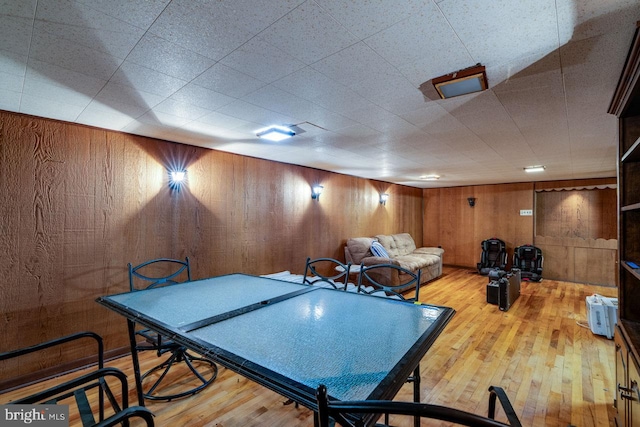 game room featuring hardwood / wood-style floors and wood walls