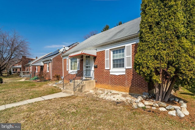 bungalow-style home with brick siding and a front lawn