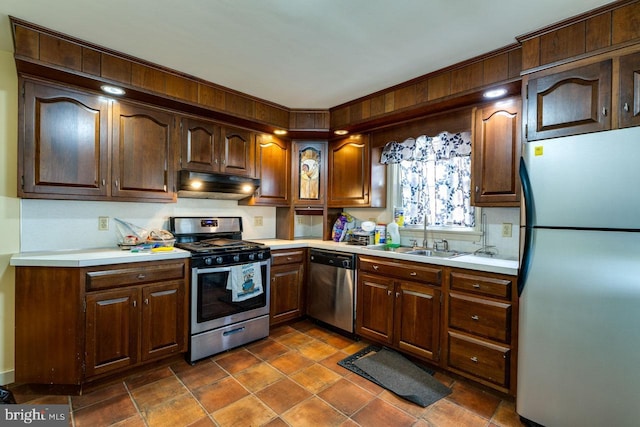 kitchen featuring under cabinet range hood, light countertops, appliances with stainless steel finishes, and a sink