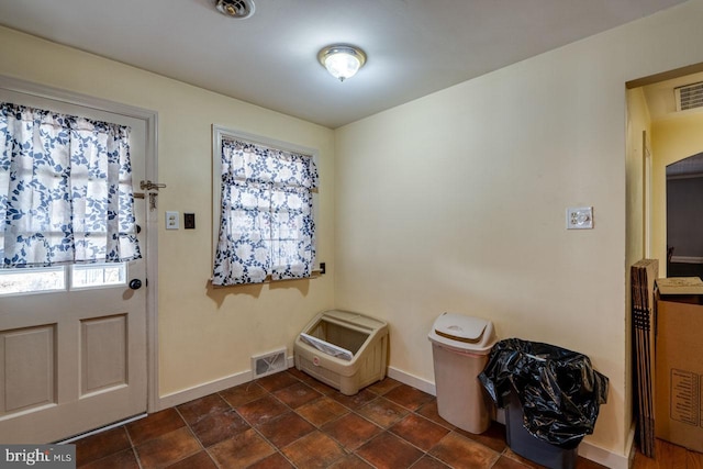 foyer entrance featuring dark tile patterned floors, visible vents, and baseboards