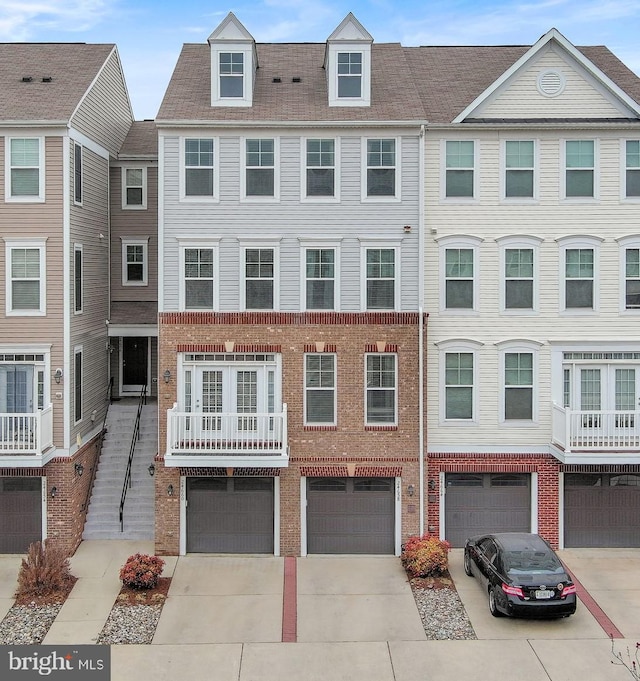 multi unit property featuring a garage, brick siding, and driveway