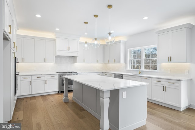 kitchen with a sink, light stone countertops, light wood-style floors, and appliances with stainless steel finishes