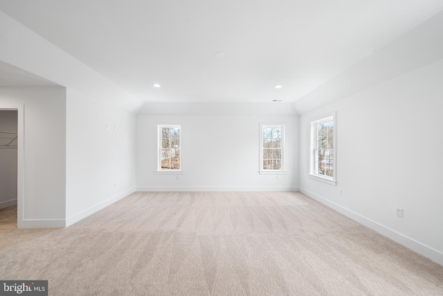 spare room with vaulted ceiling, light colored carpet, and baseboards