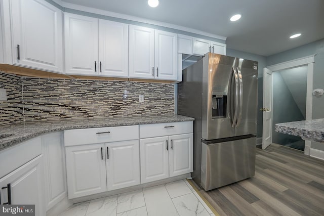 kitchen with backsplash, recessed lighting, stainless steel fridge, white cabinets, and light stone countertops