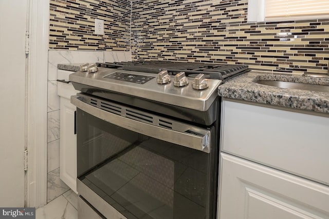 details with white cabinetry, tasteful backsplash, and stainless steel gas stove