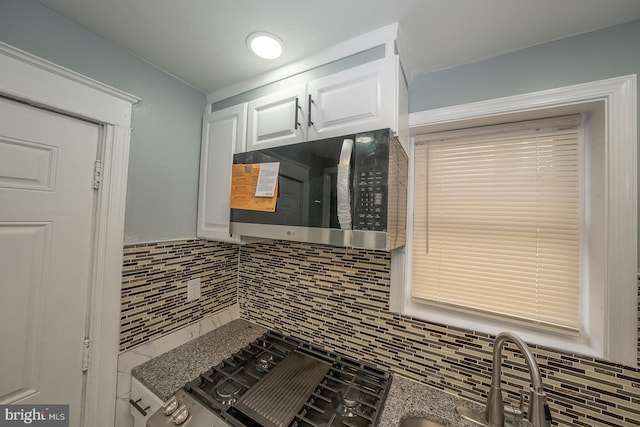 kitchen featuring stainless steel microwave, white cabinets, and tasteful backsplash