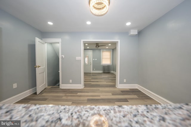 unfurnished bedroom with recessed lighting, radiator, baseboards, and wood finished floors