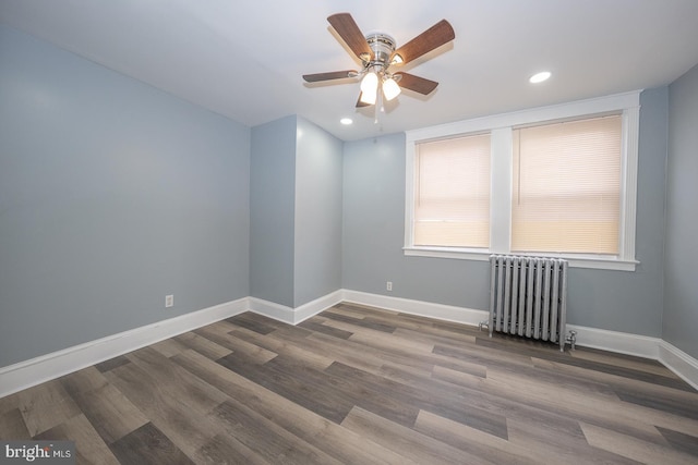 empty room with radiator, baseboards, recessed lighting, wood finished floors, and a ceiling fan