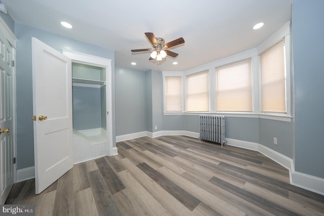 unfurnished bedroom featuring recessed lighting, radiator, baseboards, and wood finished floors