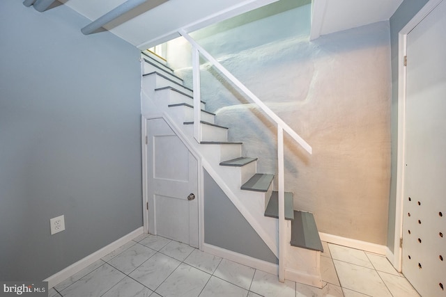 stairway featuring baseboards and marble finish floor