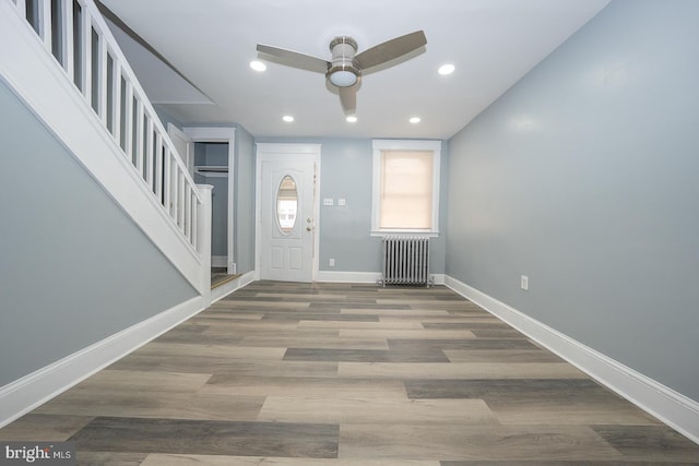 foyer with radiator, baseboards, stairs, wood finished floors, and a ceiling fan