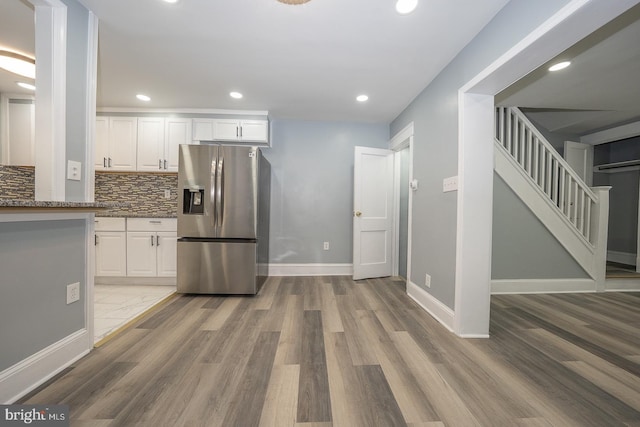 kitchen with tasteful backsplash, stainless steel fridge, white cabinets, and dark stone countertops