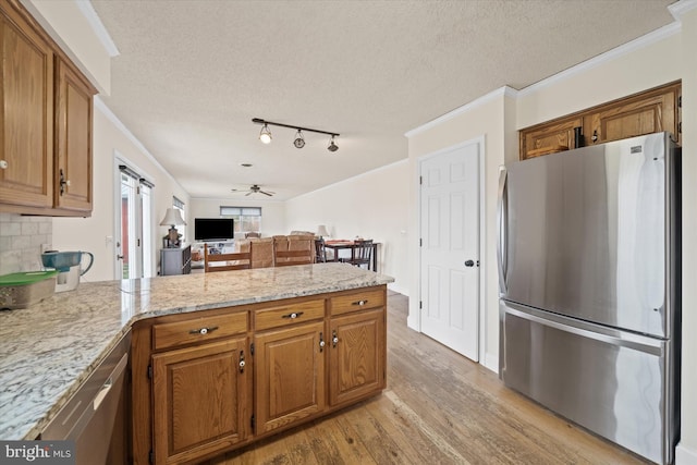 kitchen with brown cabinetry, a peninsula, a ceiling fan, and freestanding refrigerator