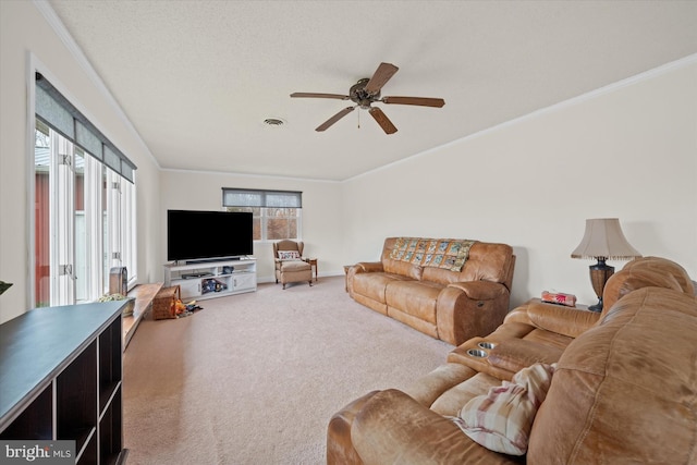 carpeted living area with visible vents, baseboards, a ceiling fan, and ornamental molding