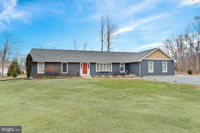 ranch-style home featuring driveway, a shingled roof, and a front yard