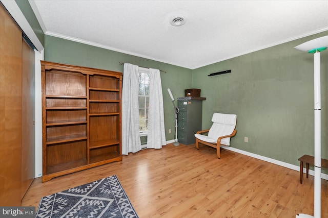 sitting room featuring visible vents, crown molding, baseboards, and wood finished floors