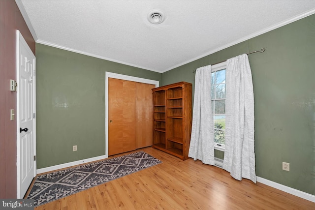 foyer entrance with wood finished floors, visible vents, baseboards, ornamental molding, and a textured ceiling