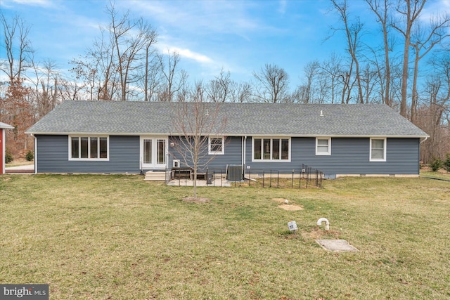 back of property with a lawn, entry steps, and a shingled roof