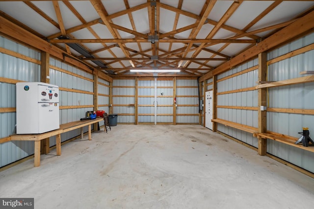 garage featuring metal wall and freestanding refrigerator