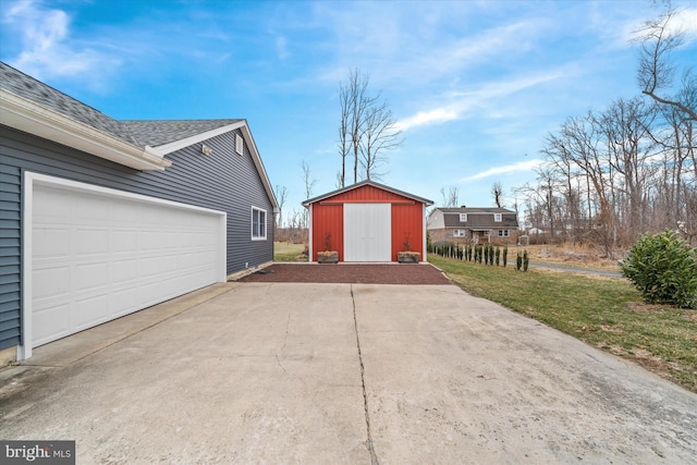 garage with driveway and a storage shed