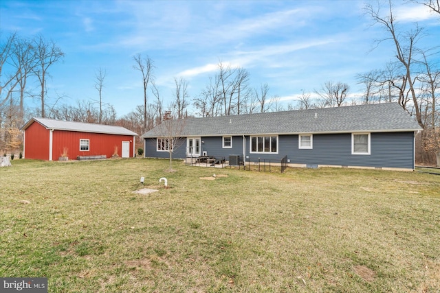 rear view of property with central AC unit, a lawn, an outdoor structure, and roof with shingles