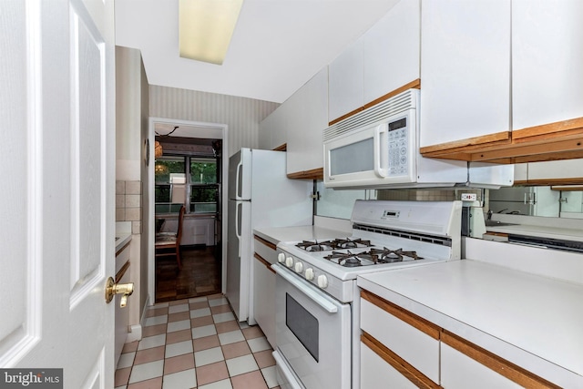 kitchen featuring white appliances, light floors, light countertops, and white cabinetry