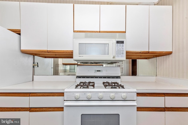 kitchen with white appliances, light countertops, and white cabinetry