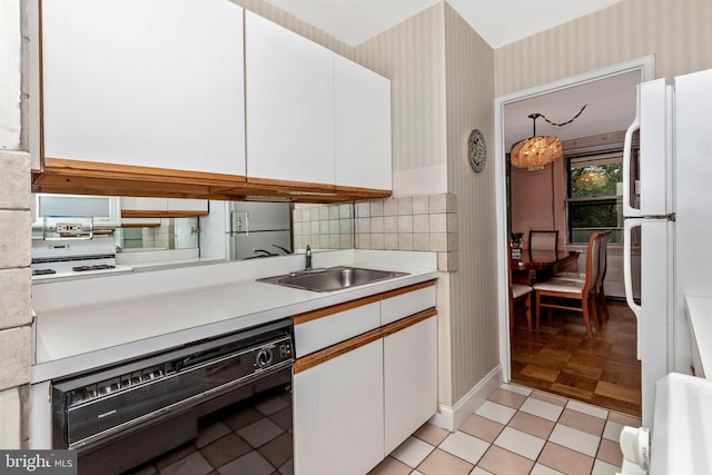 kitchen featuring a sink, dishwasher, freestanding refrigerator, and wallpapered walls