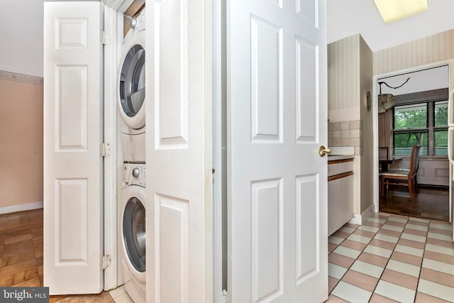 laundry area featuring laundry area, baseboards, and stacked washer and dryer