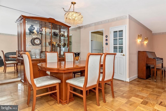 dining space featuring baseboards, a chandelier, and ornamental molding