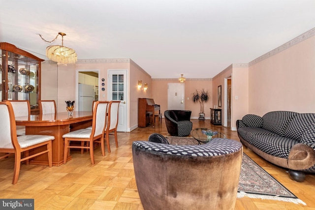 living room featuring baseboards, a chandelier, and crown molding