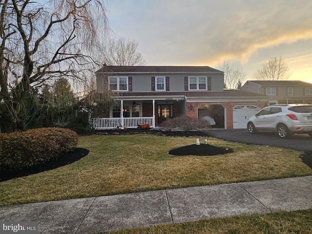 view of front of property with brick siding, aphalt driveway, covered porch, a lawn, and a garage