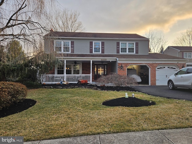 view of front of property featuring brick siding, covered porch, driveway, and a front yard