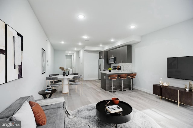 living area with recessed lighting, baseboards, and light wood finished floors