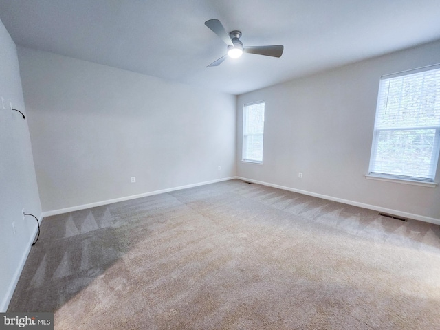 unfurnished room featuring visible vents, baseboards, carpet, and a ceiling fan