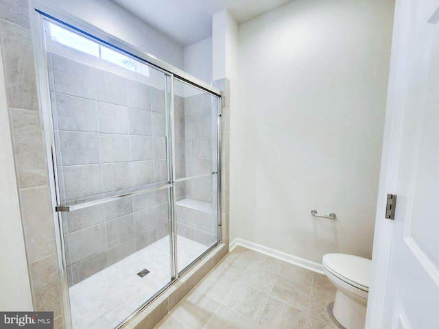 bathroom featuring tile patterned floors, a shower stall, toilet, and baseboards